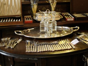 Photo shows display of silver tableware from a Paris antique shop.